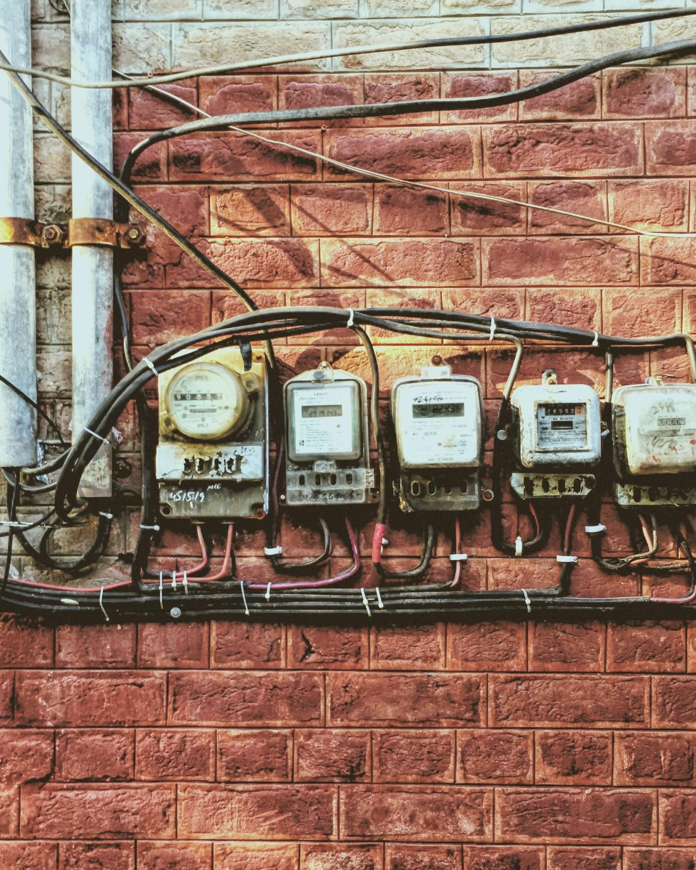 Varios medidores de luz instalados en un muro de ladrillo
